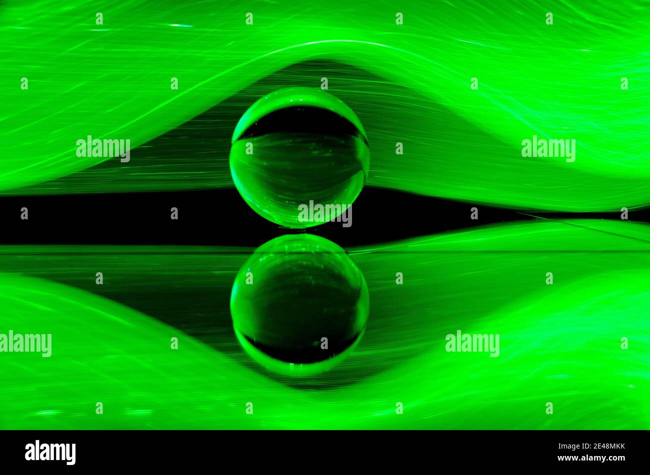 Kristallglas-Kugel und seine Reflexion auf einem abstrakten Grün lightwave Hintergrund Stockfoto