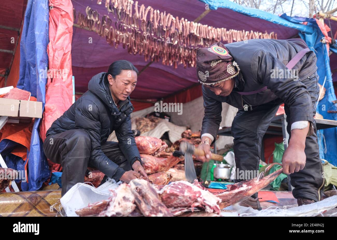 Lhasa, Chinas Autonome Region Tibet. Dezember 2020. Hirten schneiden Fleisch in Lhasa, der Hauptstadt der Autonomen Region Tibet im Südwesten Chinas, 31. Dezember 2020. In Tibet wurde eine ländliche Autobahn und ein hochwertiges Straßennetz eingerichtet, das Städte und Dörfer miteinander verbindet. Der Ausbau der ländlichen Verkehrsinfrastruktur hat das Leben der Menschen hier verändert. Quelle: Jigme Dorje/Xinhua/Alamy Live News Stockfoto