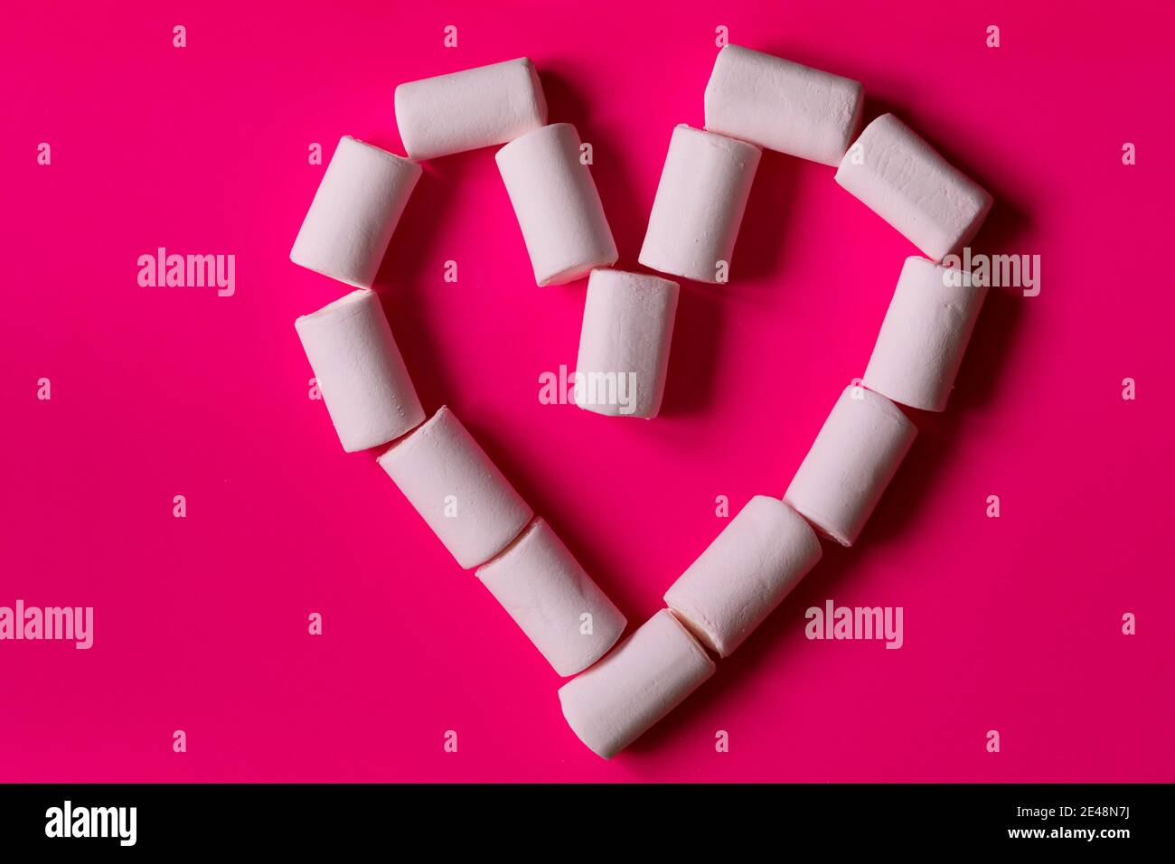 Lustige herzförmige Marshmallows für einen romantischen und süßen Snack am Valentinstag, auf einfarbigen Hintergrund. Stockfoto