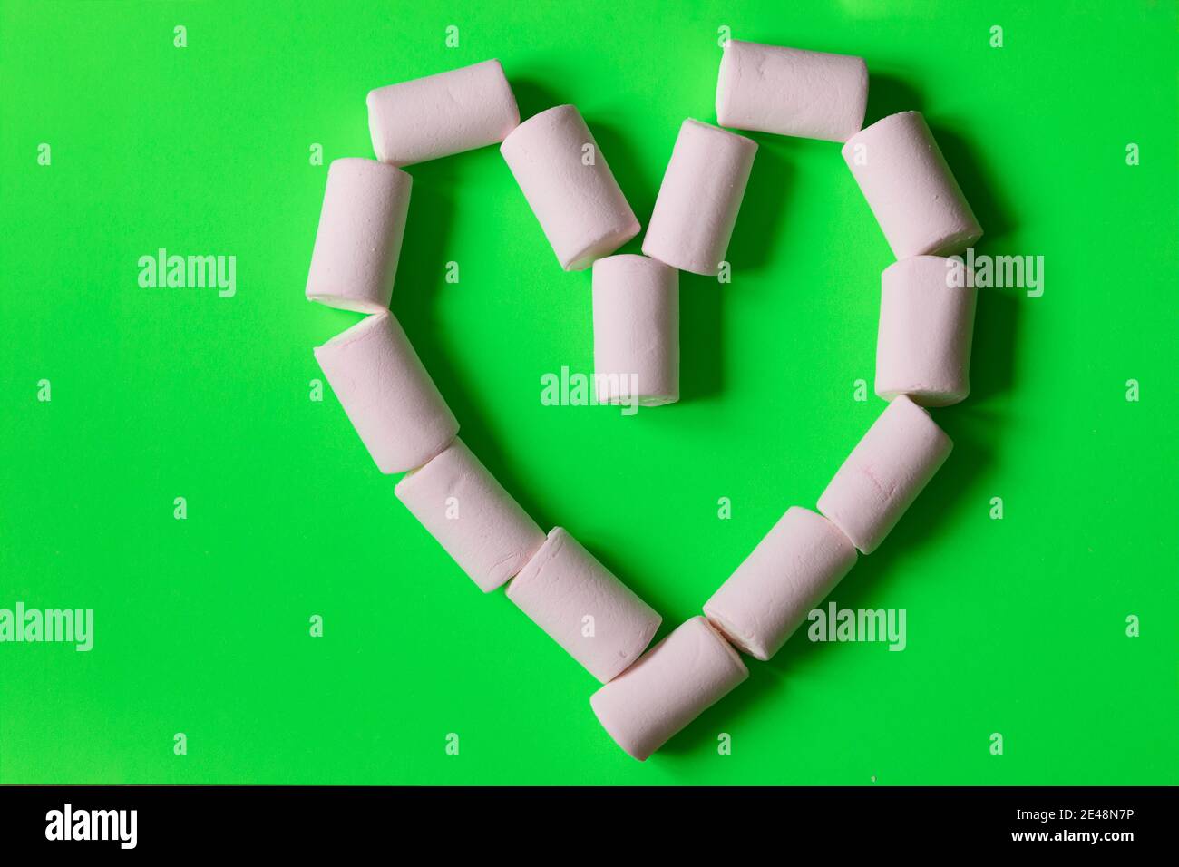 Lustige herzförmige Marshmallows für einen romantischen und süßen Snack am Valentinstag, auf einfarbigen Hintergrund. Stockfoto