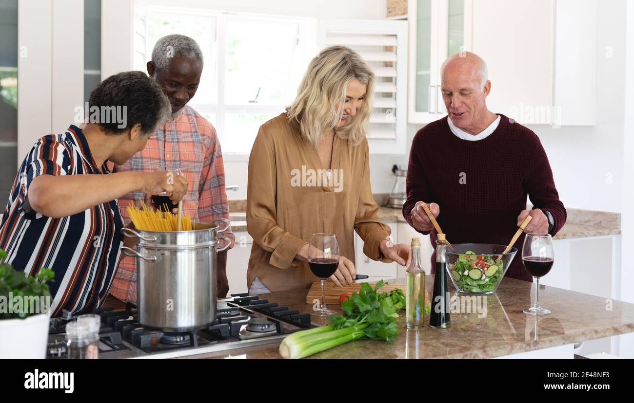 Ältere kaukasische und afroamerikanische Paare machen Pasta und Salat Zu Hause Stockfoto