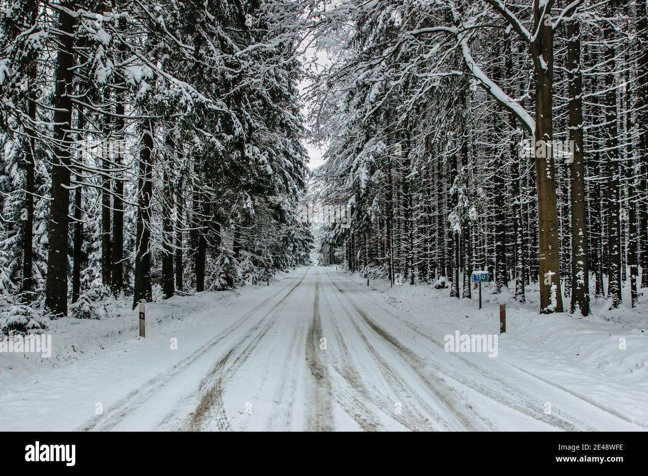 Gefährliche Strecke der Straße mit Schnee und Eis bedeckt.Snowy Straße durch Wald.Winterpanorama.Fahren in eisigen gefrorenen Landschaft.schlechte Wetterbedingungen. Stockfoto