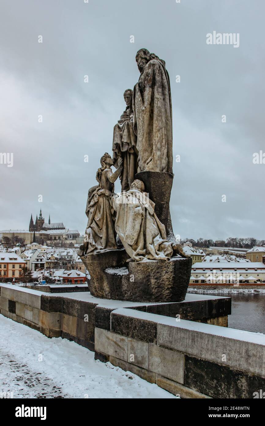 Prag, Tschechische Republik - 14. Januar 2021. Statuen auf der Karlsbrücke, Prager Burg im Hintergrund. Berühmte touristische Destination.Prag Winterpanorama. Stockfoto