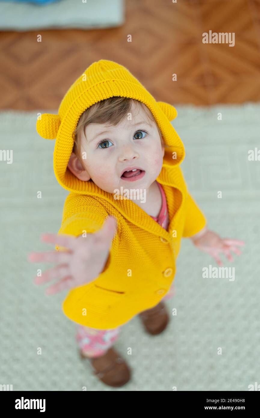 Kleines Mädchen trägt eine gelbe Jacke, die Hände erreicht Stockfoto