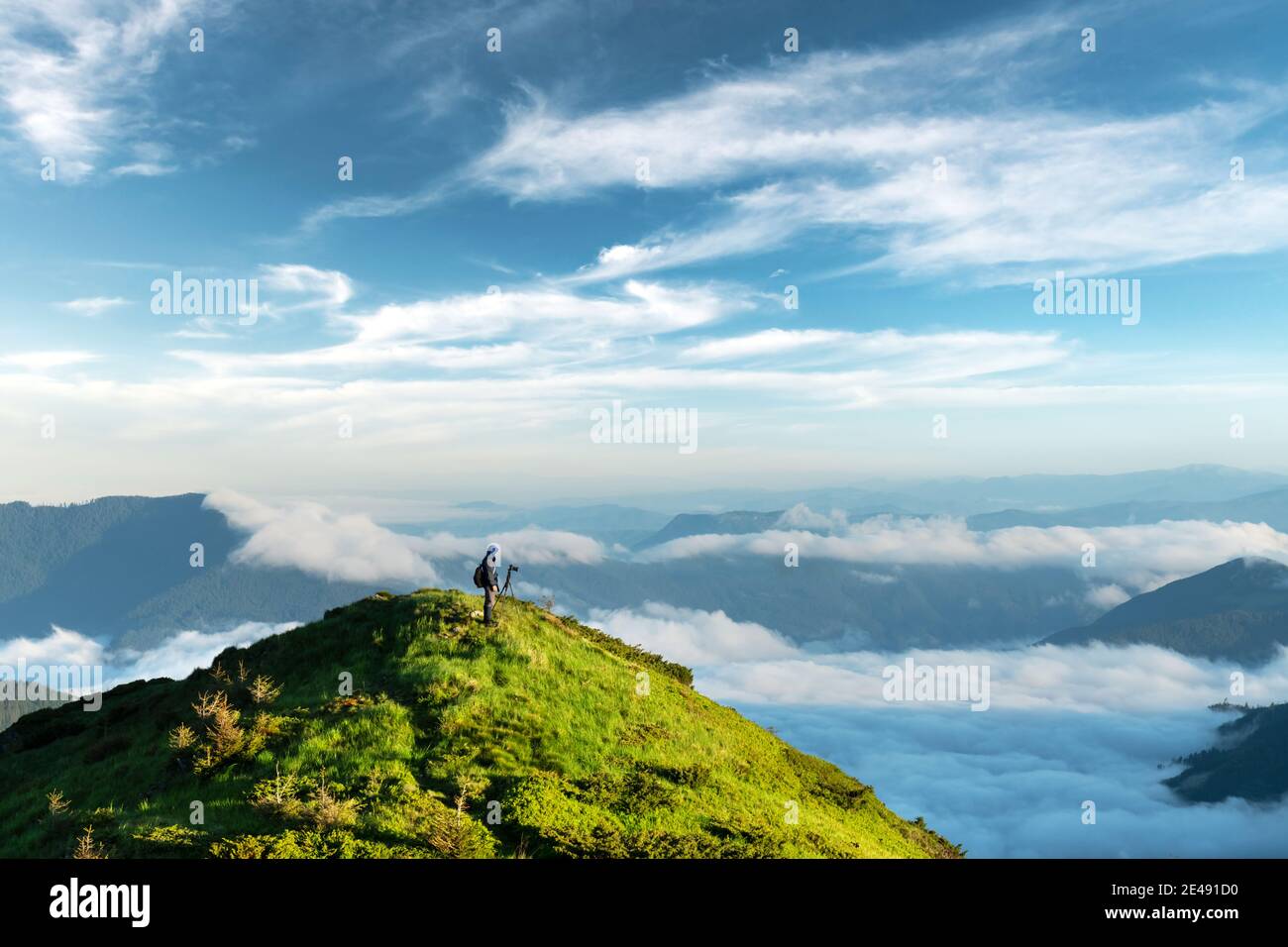 Landschaftsfotograf fotografiert neblige, wolkige Berge. Reisekonzept, Landschaftsfotografie Stockfoto