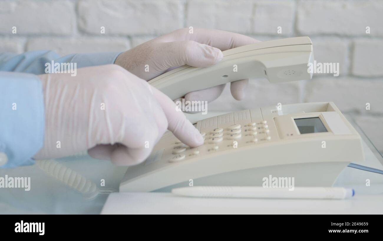 Mann trägt Schutzhandschuhe in den Händen mit Telefonkommunikation. Sozialer Distanzierender Lebensstil Stockfoto