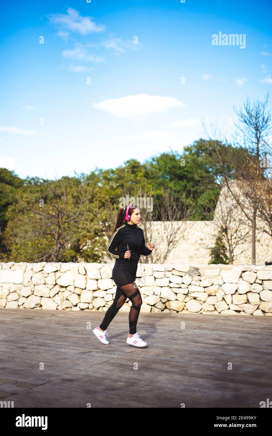 Die Sportlerin läuft beim Musikhören mit ihren Kopfhörern auf ihrem Smartphone. Stockfoto