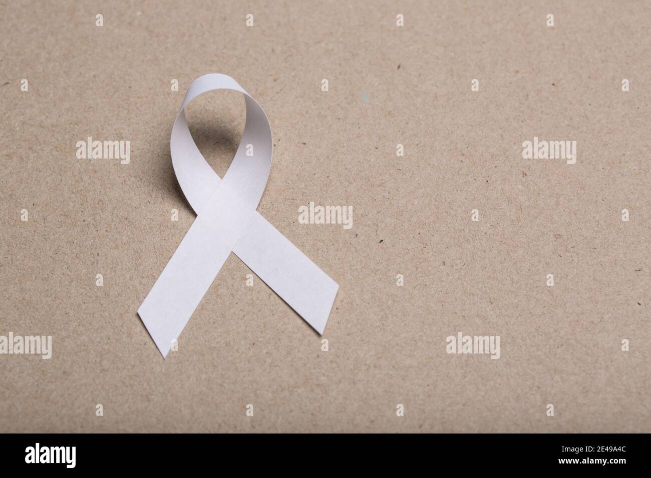 Weißes handgemachtes Awareness Papierband auf Karton Hintergrund. Stockfoto
