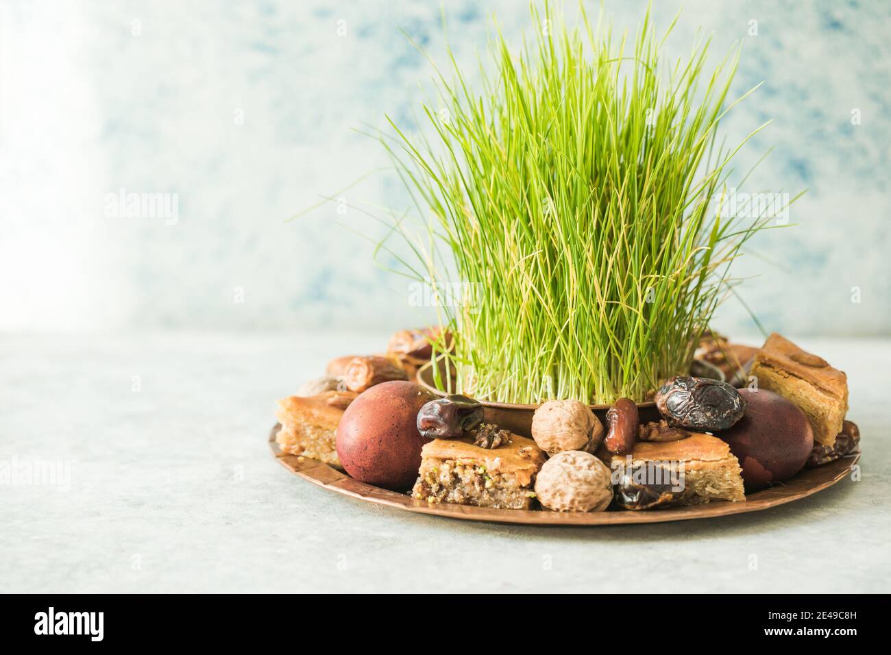 Novruz traditionelle Tablett mit grünem Weizengras semeni oder sabzi, Süßigkeiten und trockenen Früchten pakhlava auf weißem Hintergrund. Frühlings-Tagundnachtgleiche, Aserbaidschan copy sp Stockfoto