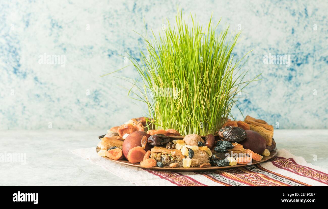 Novruz traditionelle Tablett mit grünem Weizengras semeni oder sabzi, Süßigkeiten und trockenen Früchten pakhlava auf weißem Hintergrund. Frühlings-Tagundnachtgleiche, Aserbaidschan copy sp Stockfoto