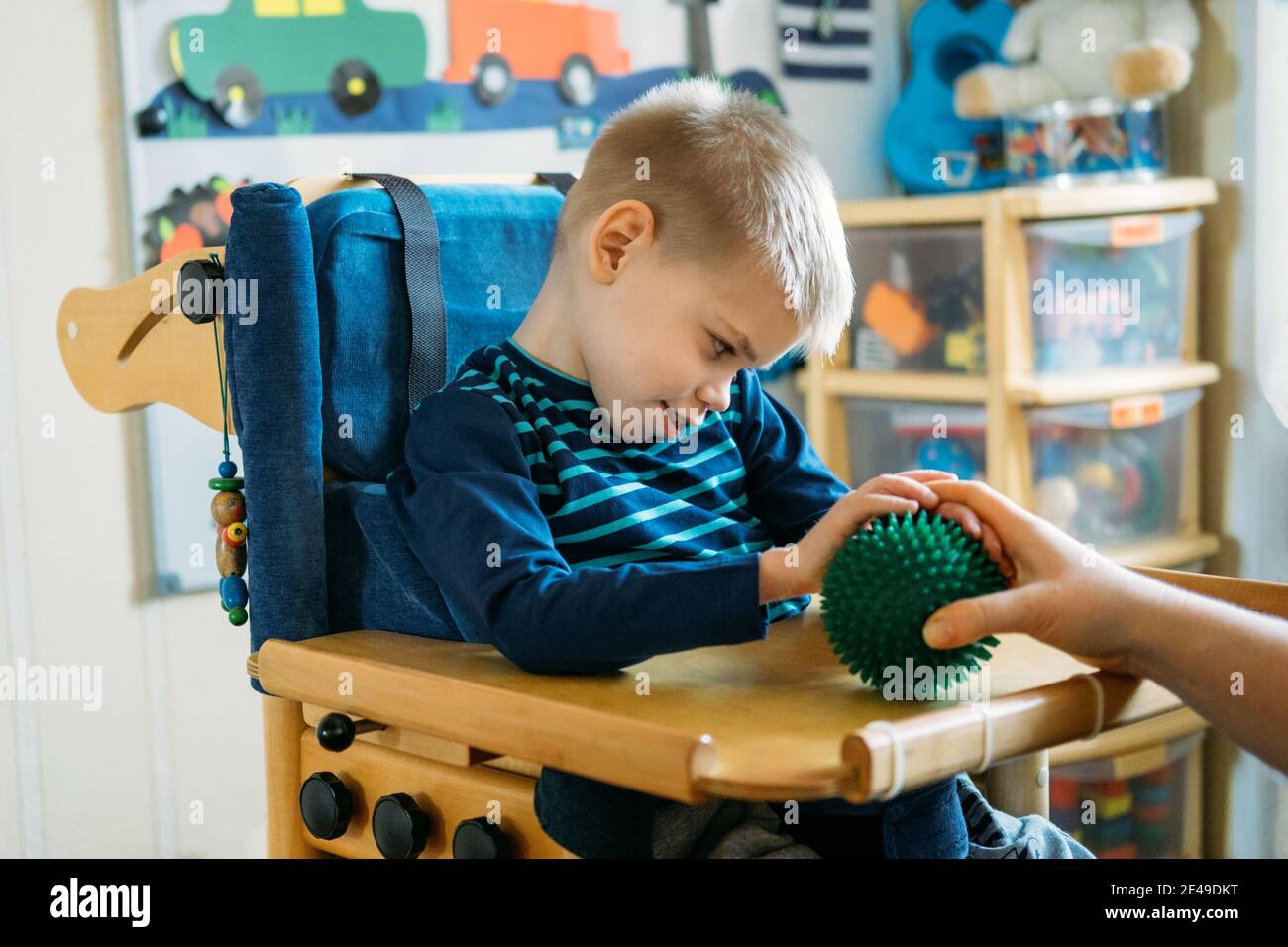 Sensorische Aktivitäten für Kinder mit Behinderungen. Vorschule Aktivitäten für Kinder mit besonderen Bedürfnissen. Junge mit Zerebralparese im speziellen Stuhl Stockfoto