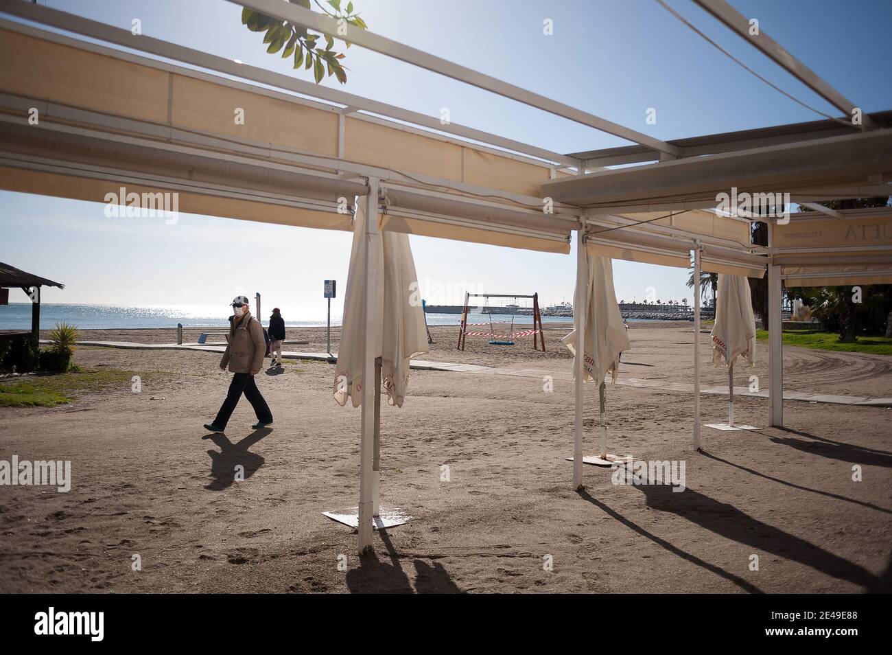 Malaga, Spanien. Januar 2021. Ein Mann mit Gesichtsmaske als Vorsichtsmaßnahme gegen die Ausbreitung von covid-19 geht an einer geschlossenen Strandbar am Strand von La Malagueta vorbei, inmitten einer Coronavirus-Pandemie.die Region Andausia erleidet einen unkontrollierten täglichen Anstieg von Coronavirus-Fällen, trotz harter Einschränkungen im täglichen Leben. In den letzten Wochen hat Andalusien täglich Tausende von Infektionen in der Region gemeldet, während der Krankenhausdruck weiter steigt. Kredit: SOPA Images Limited/Alamy Live Nachrichten Stockfoto