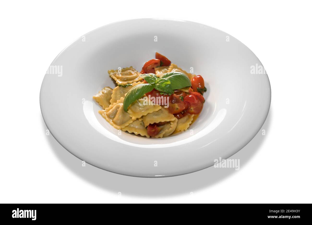 Ravioli Pasta mit Tomatensauce und in Scheiben geschnittenen Kirschtomaten und basilikumblätter in weißer Platte isoliert auf weißem Hintergrund Stockfoto