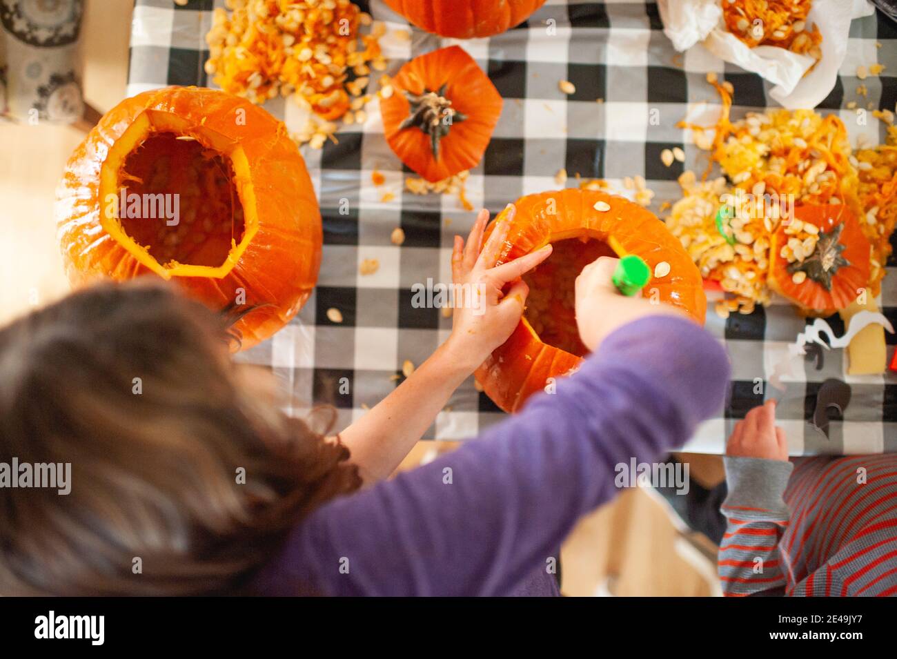 Über Kopf Blick auf Kinder Aushöhlung Kürbiskerne bei Tabelle Stockfoto