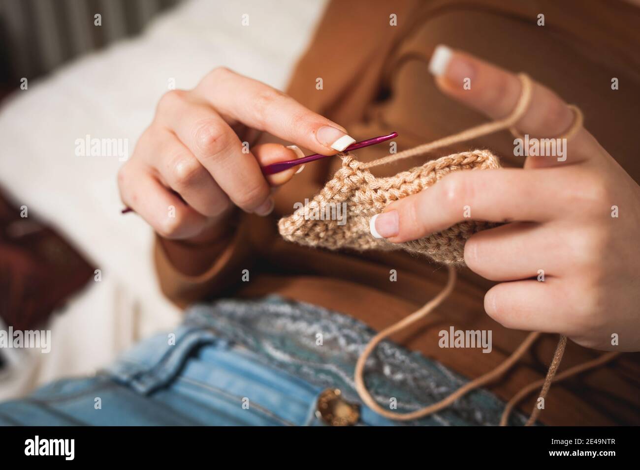 Nahaufnahme von weiblichen Händen Stricken Watte mit Nadel, Stockfoto