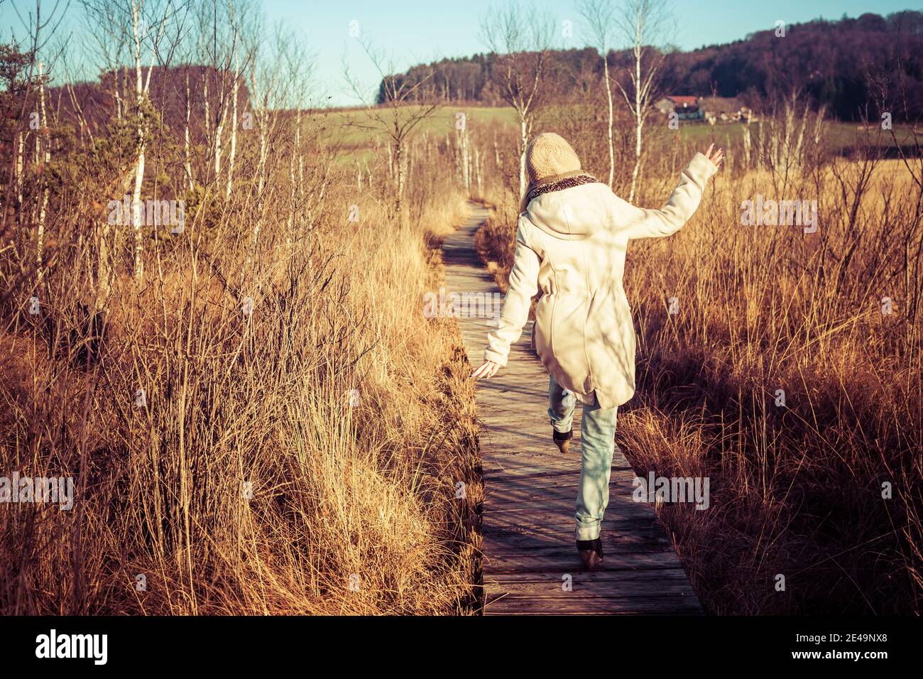 Glückliche junge Frau geht es locker, im Herbst mit goldenem Sonnenlicht draußen im ibmer Moor Österreich spazieren Stockfoto