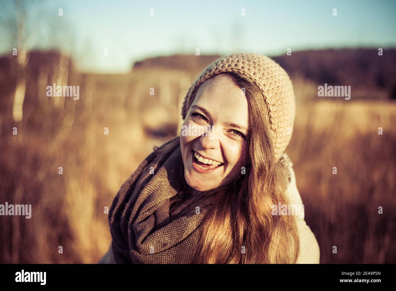 Lächelndes und glückliches Gesicht des jungen Mädchens draußen im Herbst Mit blauem Himmel im Hintergrund Stockfoto