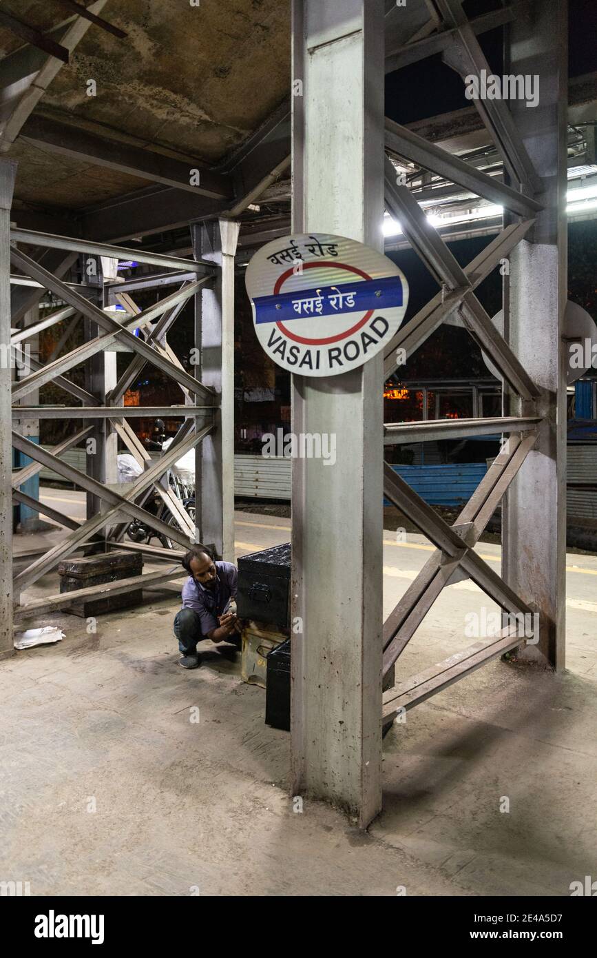 Bahnhofsmitarbeiter, die den Namen des neu beigetretenen Lokopiloten auf einem Linienkastenstamm an der Vasai Road Station, Maharashtra, Indien schreiben Stockfoto