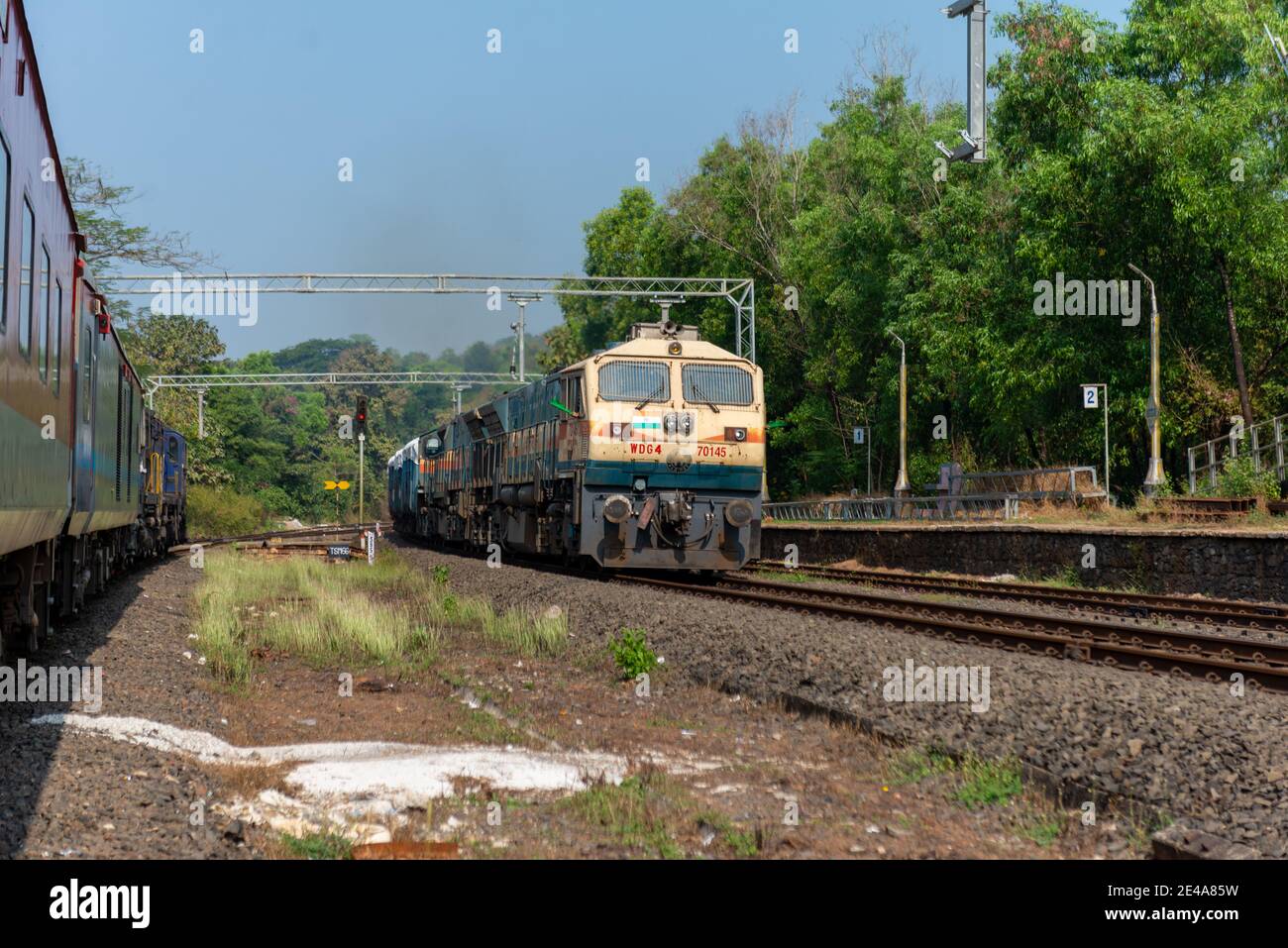 Güterzug Kreuzung 02413 Madgaon - Delhi Hazrat Nizamuddin Rajdhani Special an schönen malerischen Pernem Bahnhof auf Konkan Railway. Stockfoto