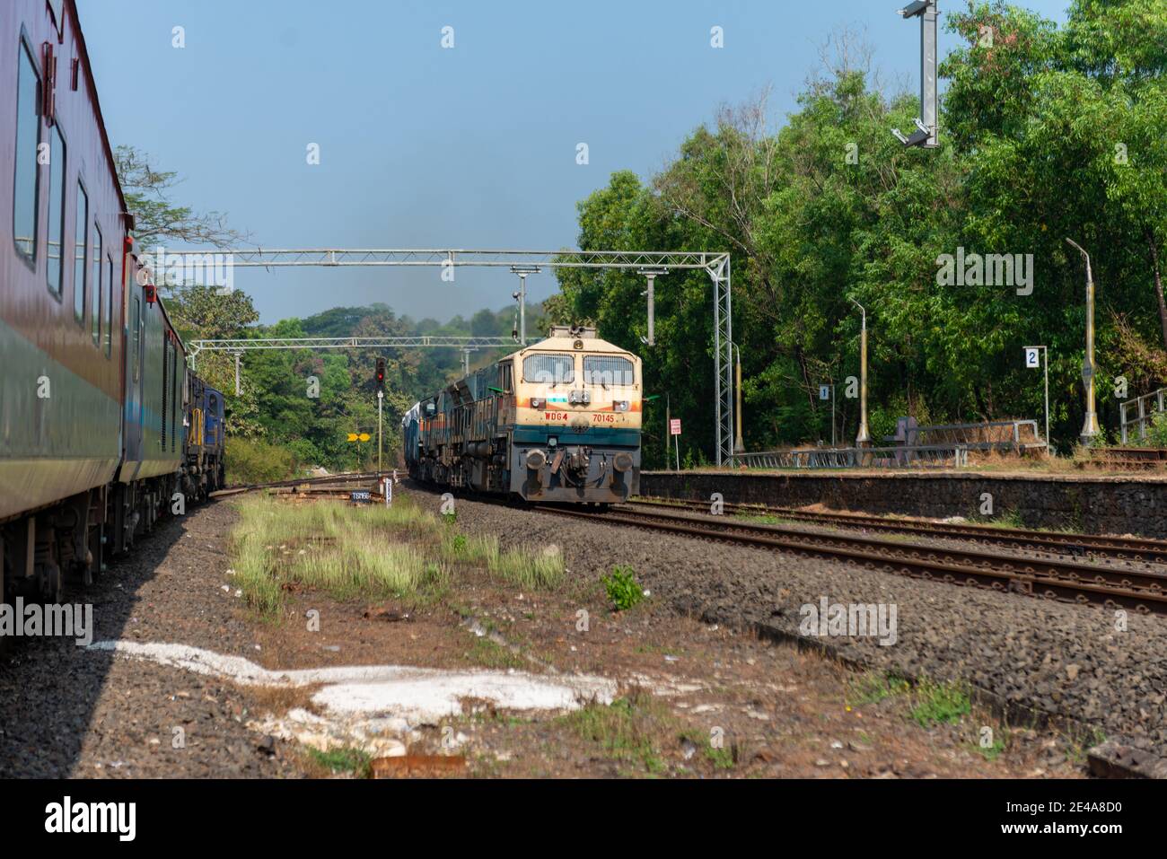 Güterzug Kreuzung 02413 Madgaon - Delhi Hazrat Nizamuddin Rajdhani Special an schönen malerischen Pernem Bahnhof auf Konkan Railway. Stockfoto