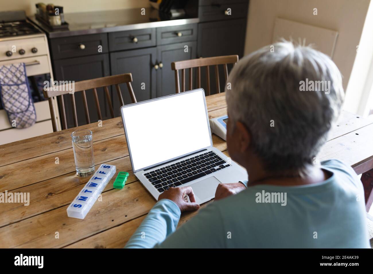 Ältere afroamerikanische Frau mit Medikamenten mit Laptop in der Küche Tabelle Stockfoto