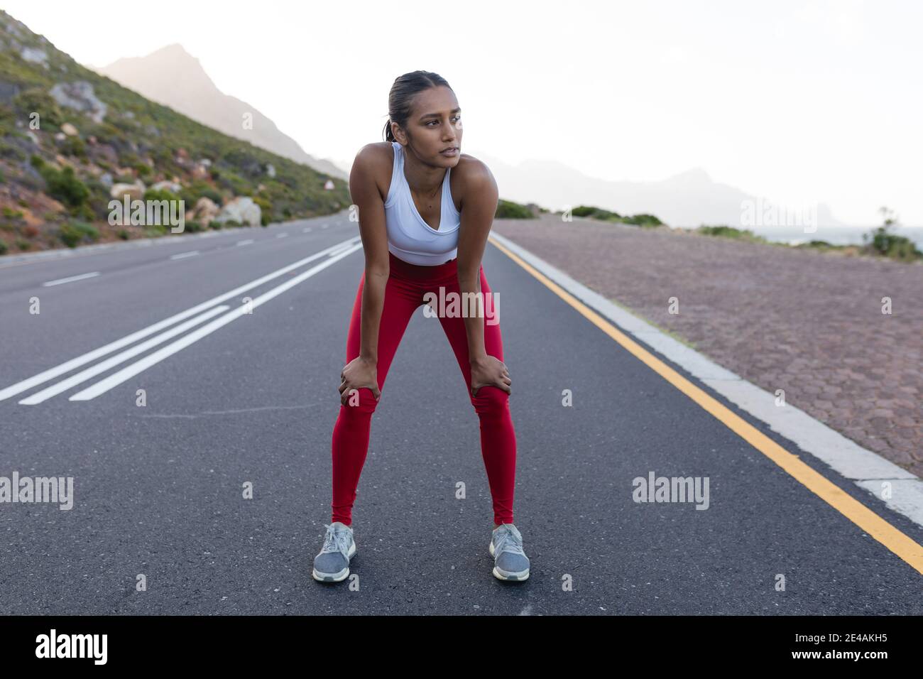 Fit afroamerikanische Frau in Sportswear stehen und ruhen auf Eine Küstenstraße Stockfoto