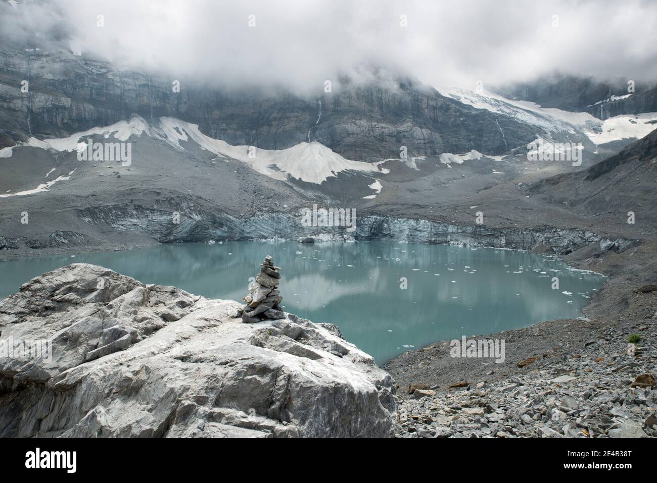 Steinmann vor einem Gletschersee, wolkig Stockfoto