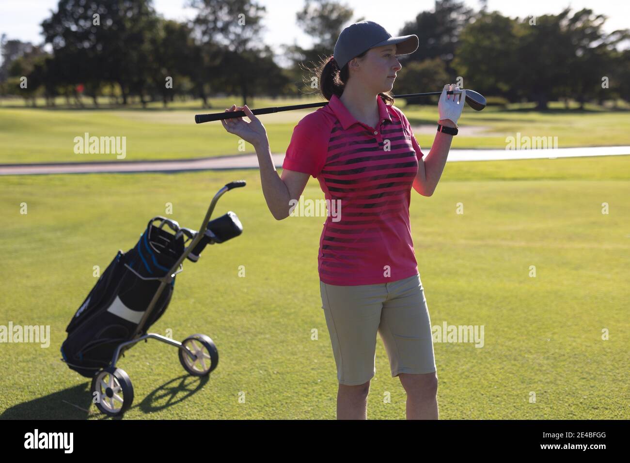 Kaukasische Frau, die auf dem Golfplatz steht und Golfschläger hält Schultern Stockfoto