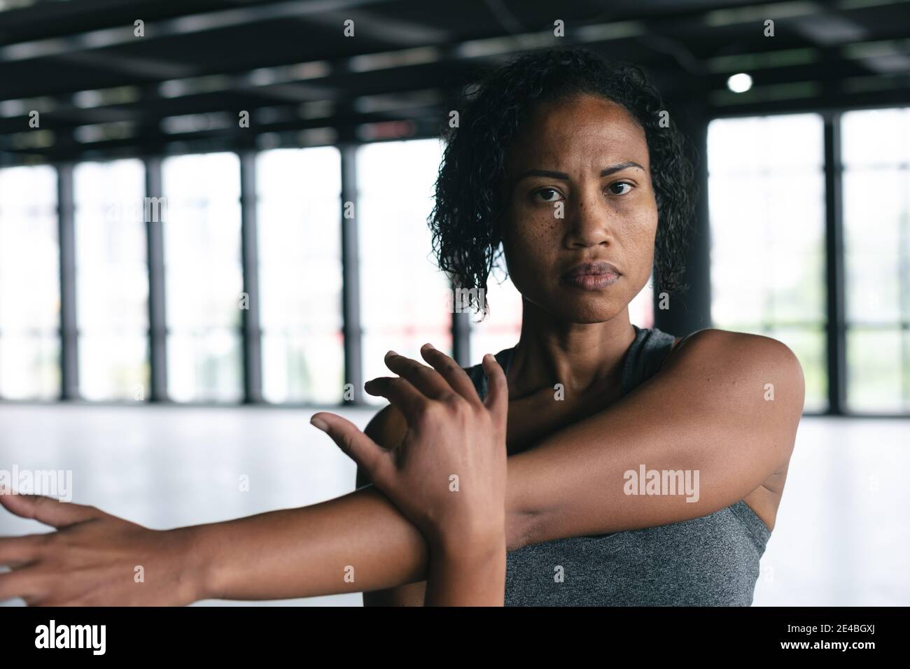 Porträt einer afroamerikanischen Frau, die in einem leeren städtischen Gebäude steht Kamera betrachten und dehnen Stockfoto