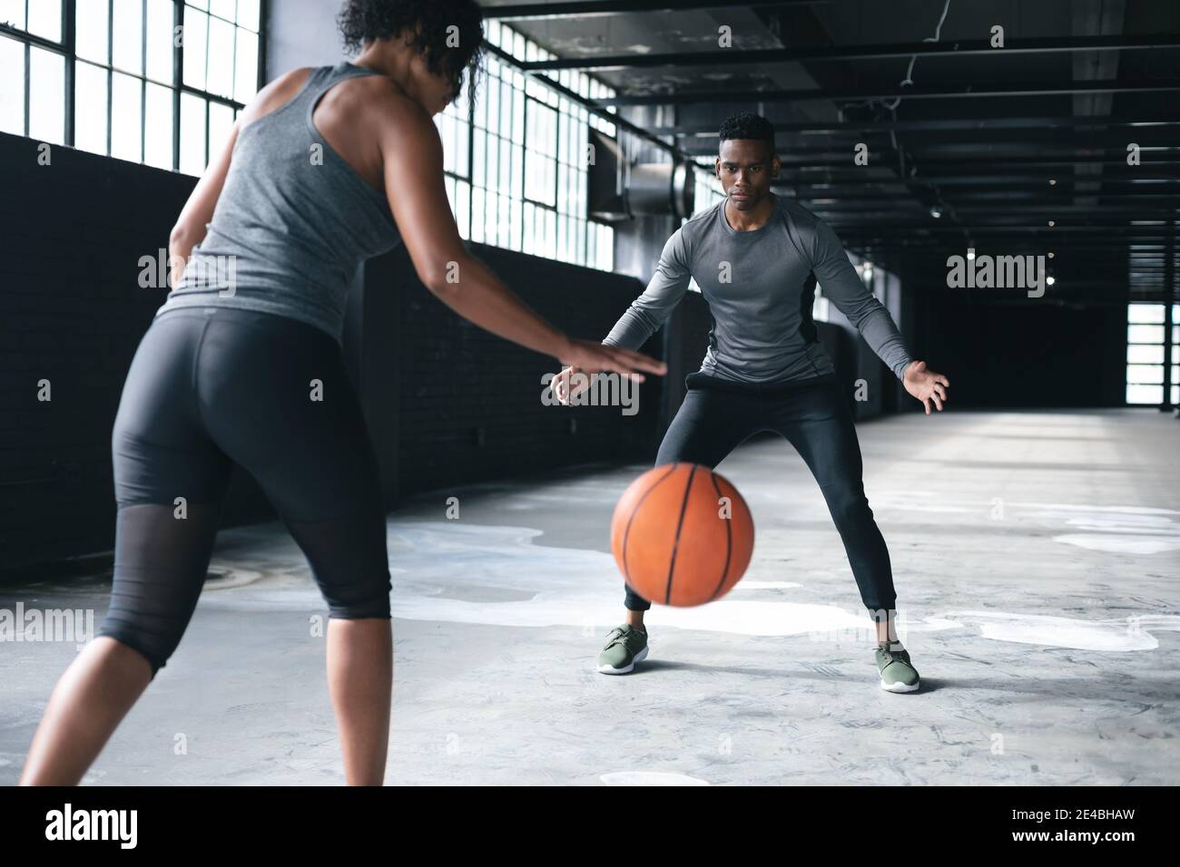 afroamerikanischer Mann und Frau stehen in einer leeren Stadt Basketball bauen und spielen Stockfoto