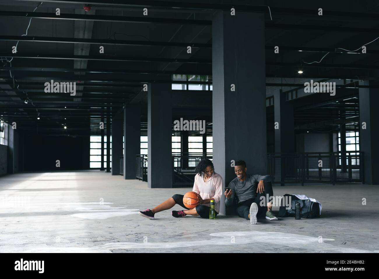 afroamerikanischer Mann und Frau sitzen in leerem Stadtgebäude Und Ruhe nach dem Basketball spielen Stockfoto