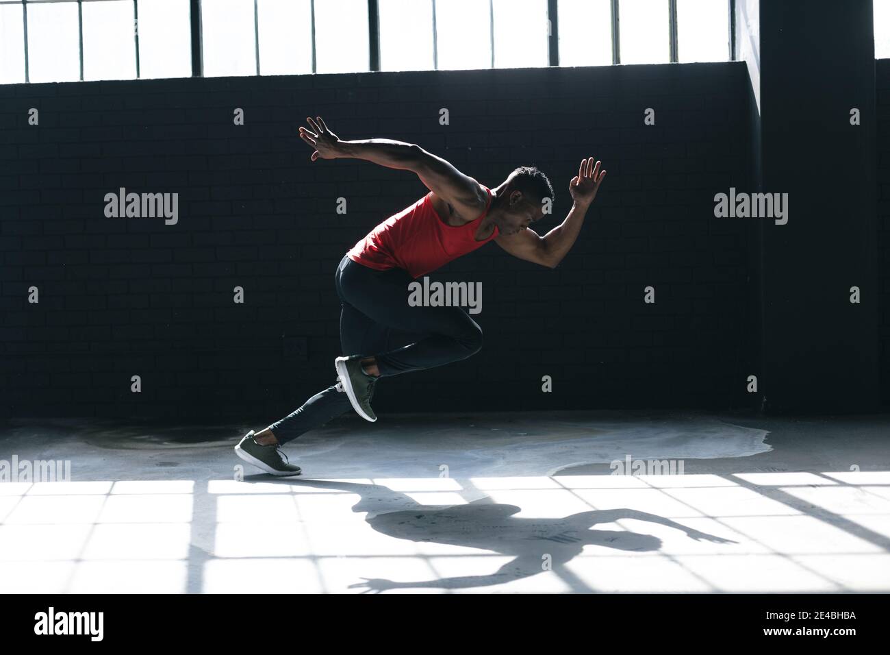 Afroamerikanischer Mann trägt Sportkleidung sprintet in leeren städtischen Gebäude Stockfoto