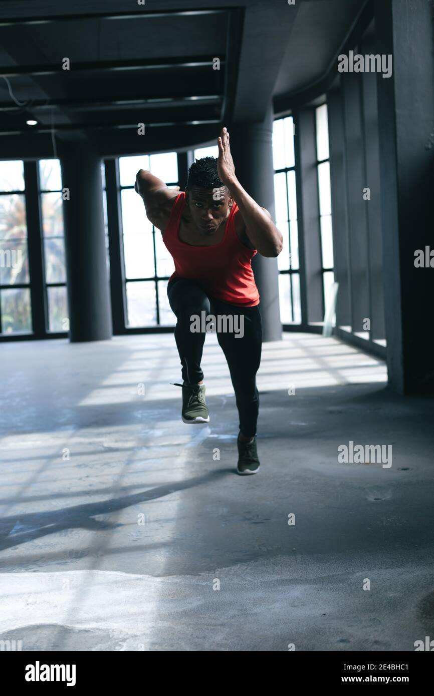 Afroamerikanischer Mann trägt Sportkleidung sprintet in leeren städtischen Gebäude Stockfoto