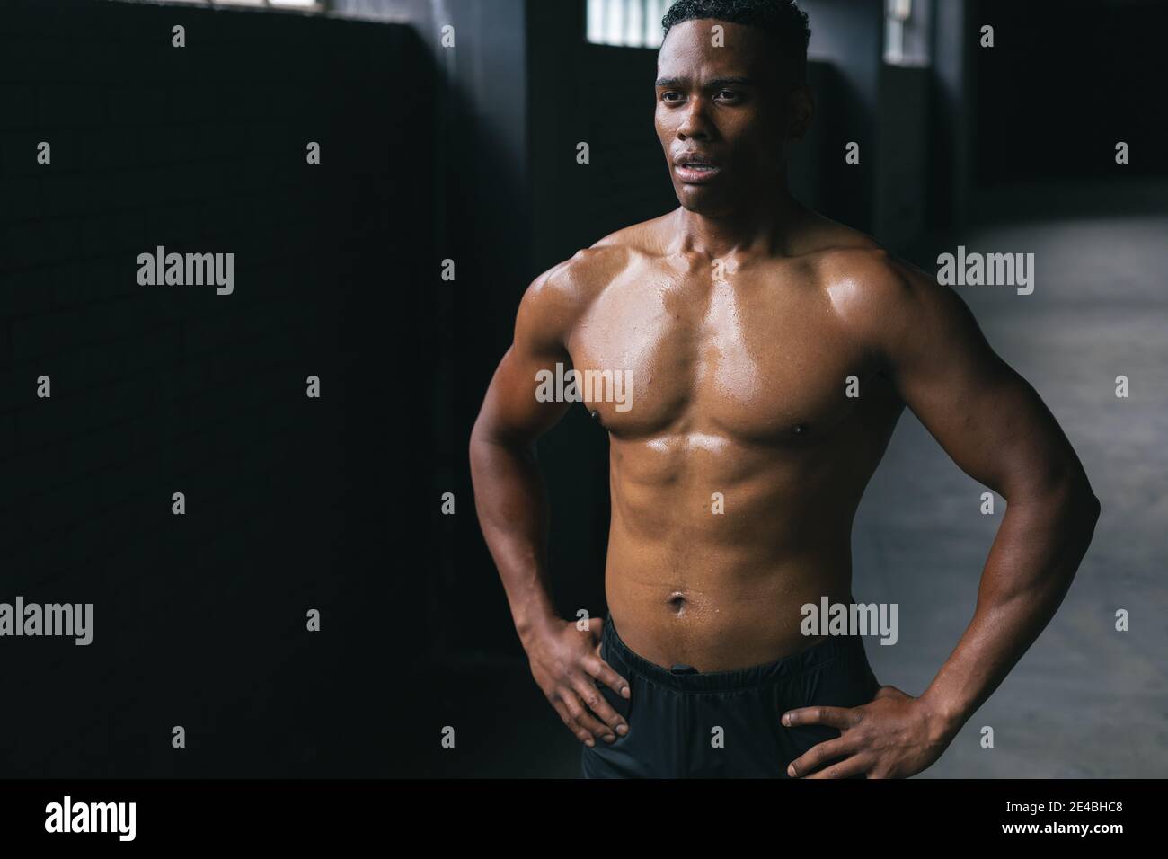 afroamerikanischer Mann steht und biegsam seine Muskeln in leer Stadtgebäude Stockfoto
