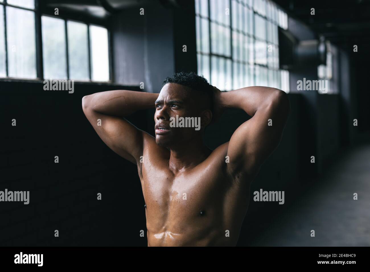 afroamerikanischer Mann steht und biegsam seine Muskeln in leer Stadtgebäude Stockfoto