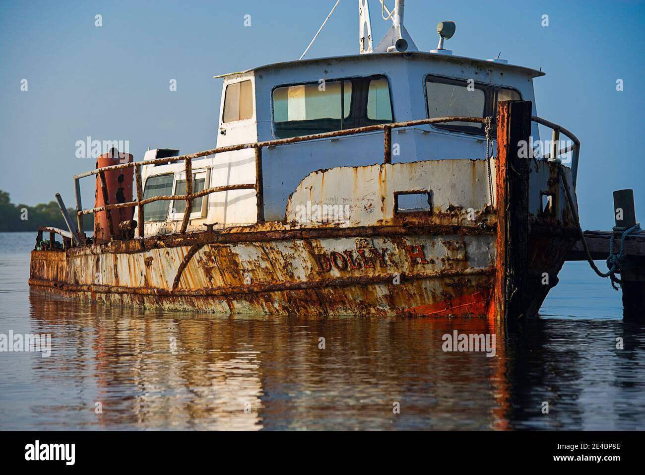 Rostiges Boot in einem See bei Sonnenaufgang, Placencia, Stann Creek, Belize vertäut Stockfoto