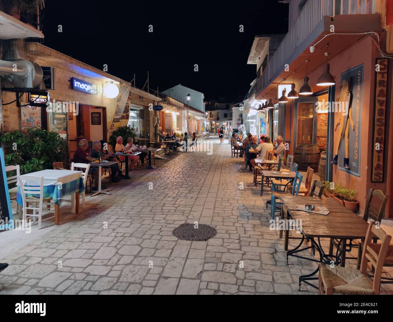 Einheimische und Touristen in Corona Zeiten vor den Tavernen in der Hauptstraße von Finikounda, Messenia, Peloponnes, Griechenland Stockfoto