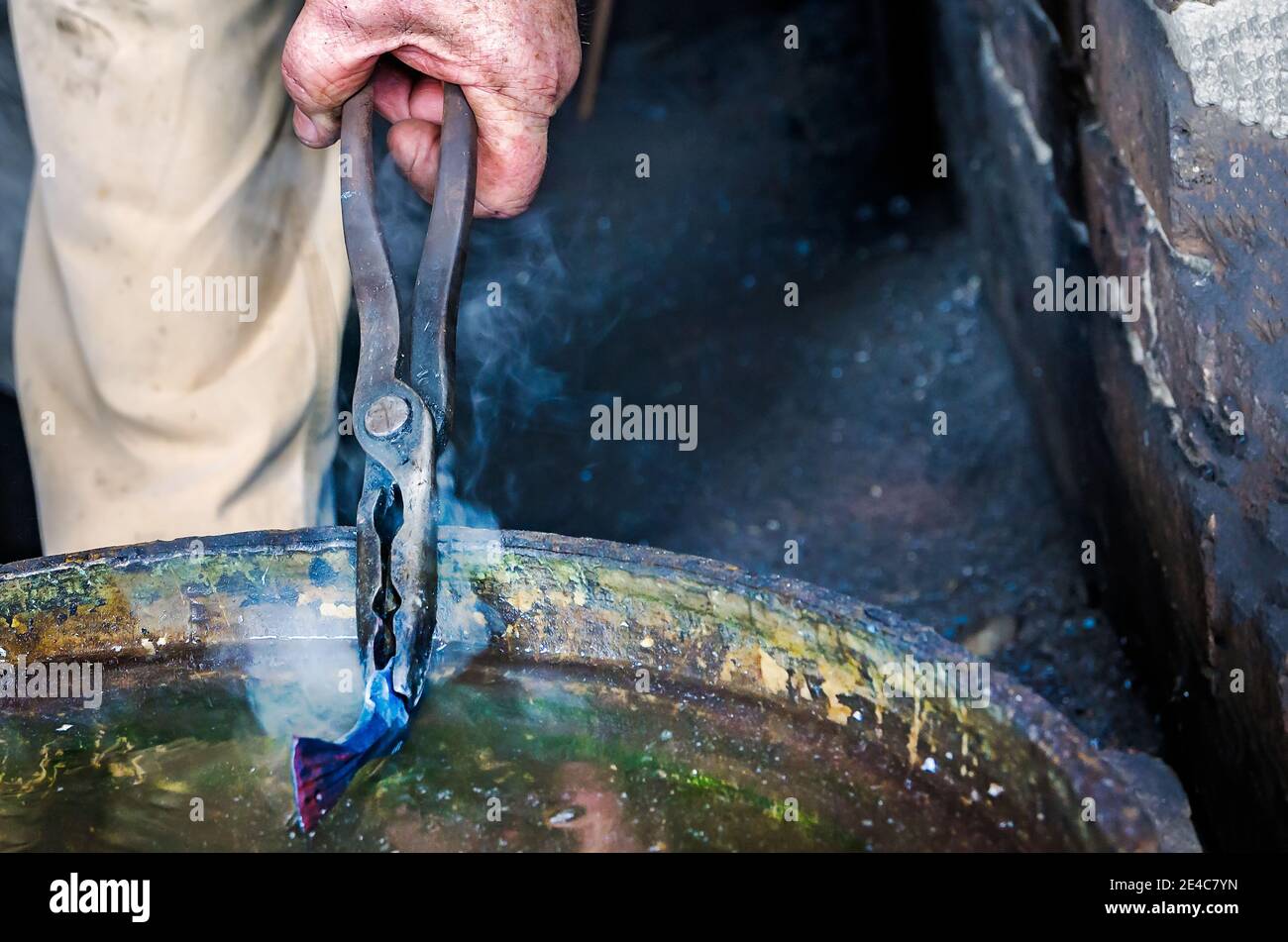 Schmied Ralph Oalmann stürzt ein heißes Stück Metall in einen Eimer Wasser in Fort Gaines, 5. August 2017, auf Dauphin Island, Alabama. Stockfoto