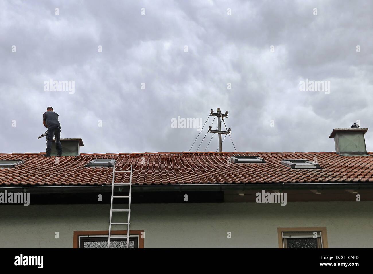 Eine Schornsteinfeger auf dem Dach reinigt einen Schornstein mit Eine Bürste Stockfoto