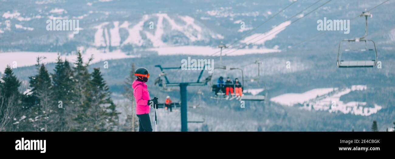 Die Skifahrerin, die vom Gipfel des Pistenberges aus Ski fährt, mit Blick auf die Landschaft und die Skifahrer im Hintergrund des Skilifts. Wintersport aktiv Stockfoto