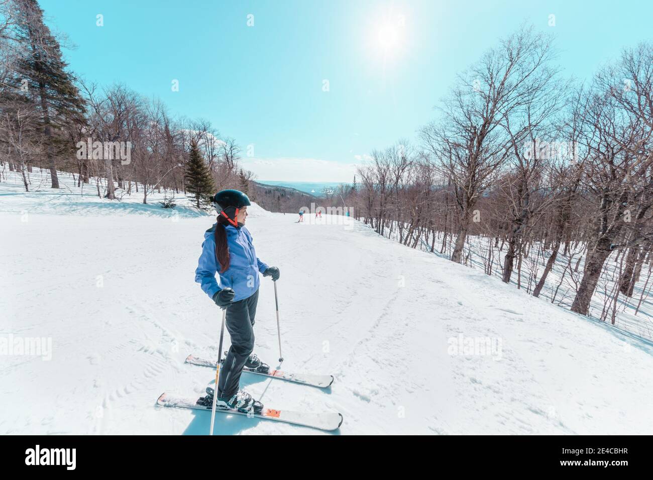 Skifahrerin, die beim Skifahren auf der Piste eine Pause einnahm. Glückliche asiatische aktive Frau, die sich an einem sonnigen Tag im Skigebiet entspannt. Wintersport-Urlaub Stockfoto