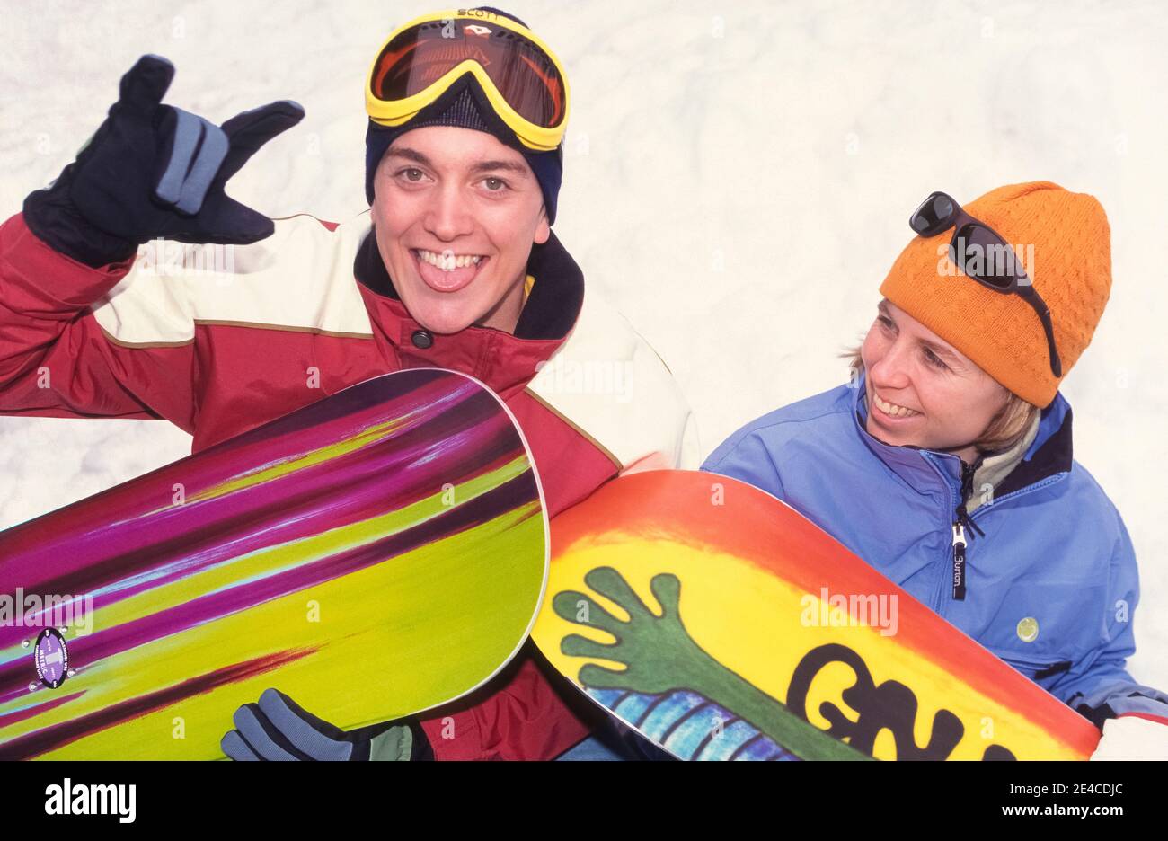 Zwei Teenager halten mit ihren farbenfrohen Snowboards für ein informelles Portrait vor einer Schneebank im Whitefish Mountain Resort in Whitefish, Montana, USA. Das Snowboarden wurde in den 1960er Jahren in den Vereinigten Staaten entwickelt und kombiniert die Elemente Skifahren, Skateboarden und Surfen. Als seine Popularität wuchs bundesweit in den nächsten zwei Jahrzehnten, einige Skigebiete zunächst verboten den Sport auf ihren Pisten. Alle vier Jahre seit 1998 bekommt das Snowboarden bei den Olympischen Winterspielen internationale Aufmerksamkeit. Stockfoto