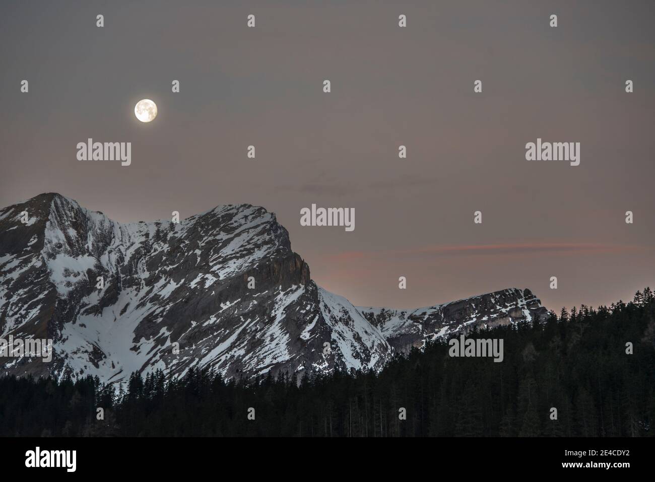 Vollmond bei Tagesanbruch in den winterlichen Bergen Stockfoto