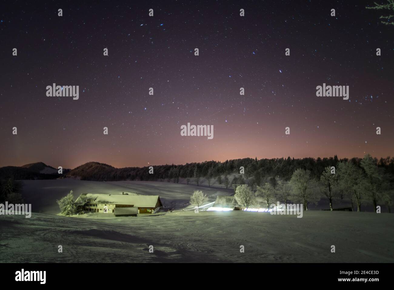 Nachts unter den Sternen, Bauernhof mit Licht im Stall Stockfoto