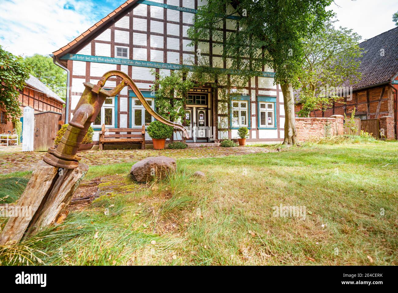 Ein restauriertes Hallhaus eines mittelalterlichen Runddorfes, alte Handpumpe im Vordergrund Stockfoto