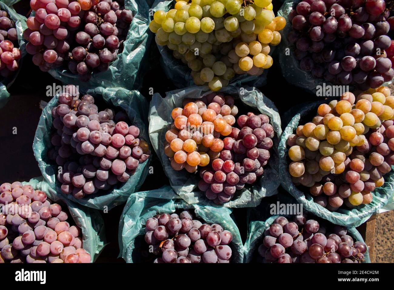 Bündel von weißen und roten / lila / schwarzen Trauben alle auf einem Markt mit lebendigen Farben und gesundes Aussehen platziert. Die Früchte sind lecker, voller Vitamine Stockfoto