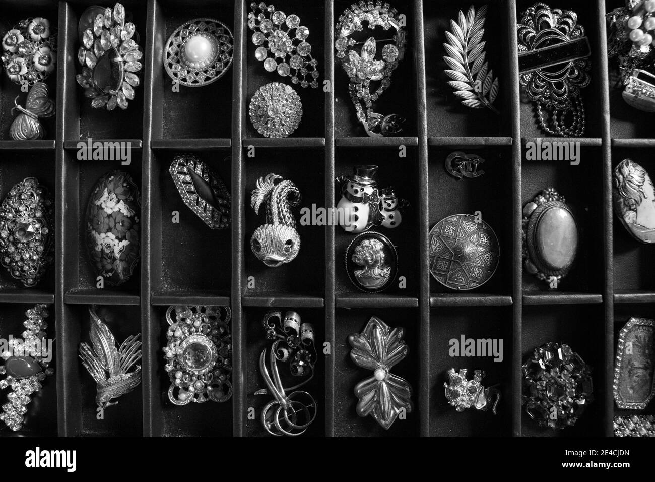 Viele verschiedene Broochs und Pins in einer schwarzen Box angezeigt. Es gibt goldene Stifte, Edelsteine, verschiedene Formate und Farben. Silber und Eisen Stockfoto