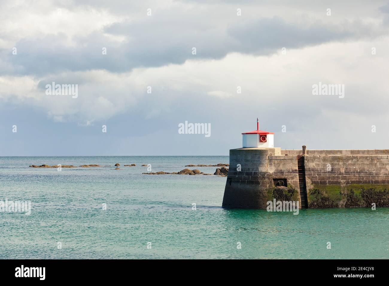 Sturmwolken ziehen über die mächtige Mauer des Barfleur Hafens. Möwen fliegen herum. Cotentin Peninsula, Normandie, Frankreich Stockfoto