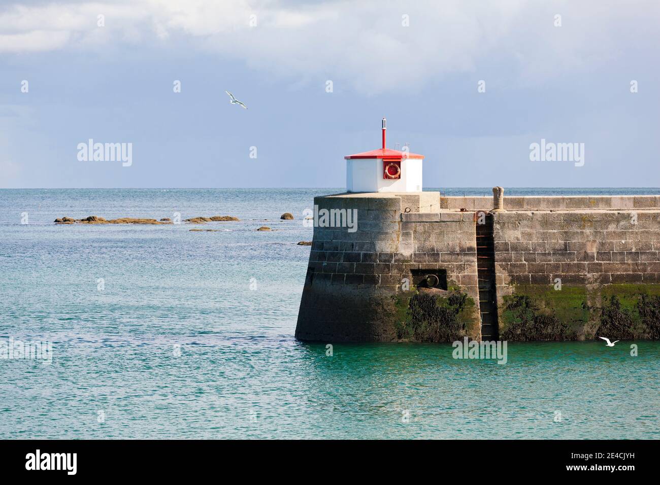 Sturmwolken ziehen über die mächtige Mauer des Barfleur Hafens. Möwen fliegen herum. Cotentin Peninsula, Normandie, Frankreich Stockfoto