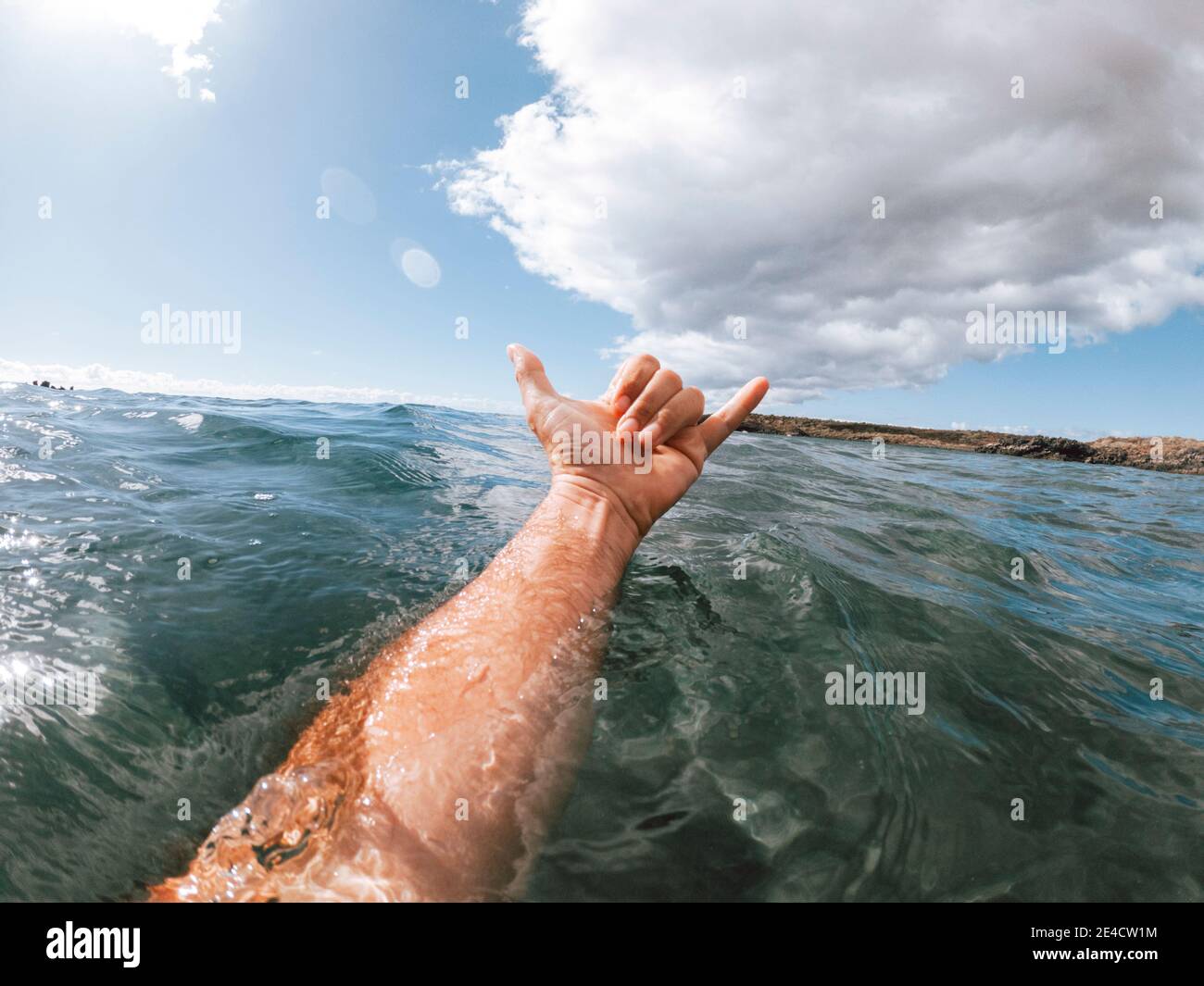 Mann reicht das Surfschild hallo aus dem blauen Himmel meerwasser mit Küste und schönem Himmel im Hintergrund - Konzept von Menschen und Sommerurlaub Stockfoto